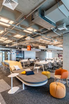 an office with chairs, tables and couches in the middle of the floored area