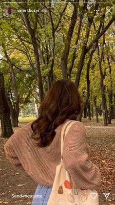 a woman is walking through the park with her hand on her hip and looking at trees