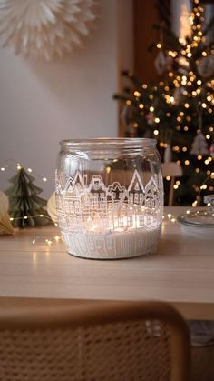 a lit candle sits on a table in front of a christmas tree and other decorations