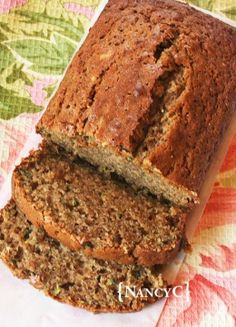 a loaf of banana nut bread on top of a flowered table cloth next to a knife