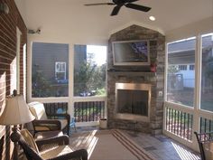 a living room with two chairs and a television on the wall in front of a fireplace