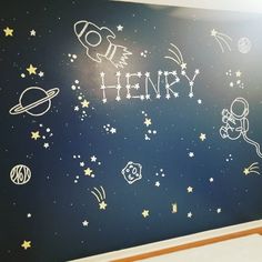 a child's room with stars and planets painted on the wall in white chalk