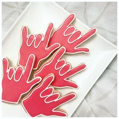 three decorated cookies sitting on top of a white plate with pink icing and writing