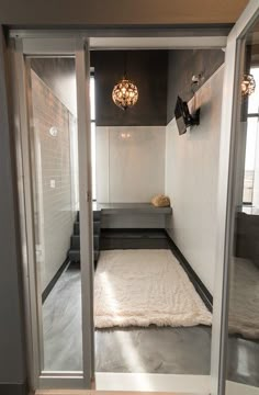 an open door leading into a bathroom with a rug on the floor and lights hanging from the ceiling