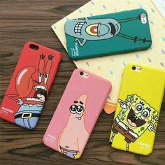 three cartoon phone cases sitting on top of a wooden table