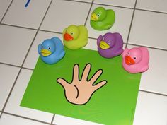 several rubber ducks sitting on top of a tiled floor next to a hand print in the middle