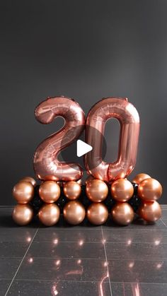 the number 20 is surrounded by balloons in front of a black wall and tiled floor