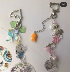 three key chains with charms attached to them on top of a white table next to a plate