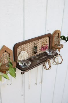 a shelf with jewelry and bracelets on it next to a wall mounted planter