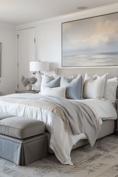 a large white bed sitting in a bedroom next to a painting on the side of a wall