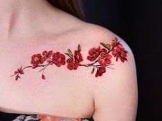 a woman's shoulder with red flowers and leaves on the top of her chest