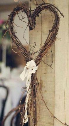 a heart shaped wreath hanging from the side of a wooden door with vines and bow