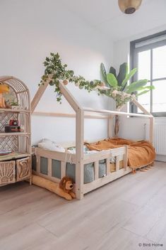 a child's bed with a house shaped structure next to it and a plant in the corner