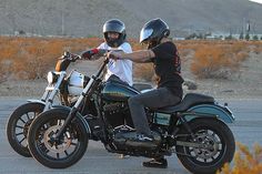 two people riding on the back of motorcycles