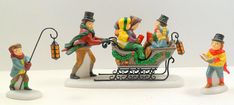 three figurines of people riding in a sleigh