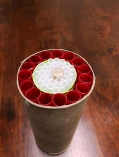 a cup filled with red cups sitting on top of a wooden table