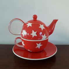 a red tea pot and saucer with white stars on it