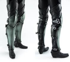 the legs and feet of a man in black leather garb with metal straps on them