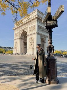 a man standing next to a lamp post in front of the arc de trioe