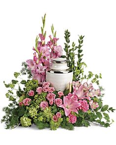 a white vase filled with pink flowers and greenery