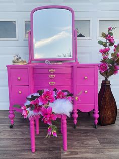 a pink dresser with flowers and a mirror