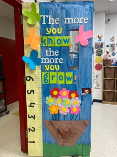 a growth chart with flowers and butterflies on it in front of a classroom door that says, the more you know the more you grow