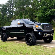 the black truck is parked on the side of the road in front of some trees