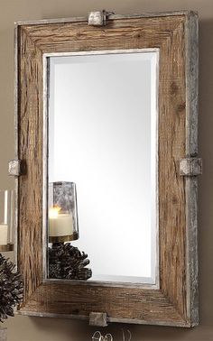 a mirror that is sitting on top of a shelf next to a candle and some pine cones