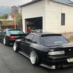 two black cars parked next to each other in front of a building