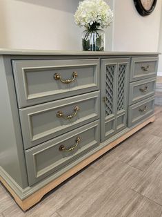 a gray dresser with gold handles and drawers in a living room or dining room area