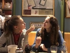 two women sitting at a table talking to each other