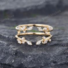 a gold ring with white stones on top of a stone slab in front of a rock