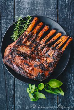 grilled pork chops on a black plate with fresh herbs