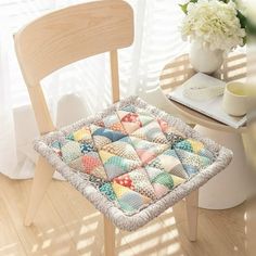 a wooden chair with a cushion on top of it next to a table and flowers