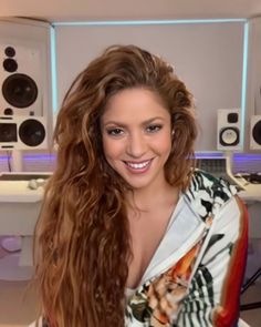 a woman with long hair standing in front of some audio equipment and smiling at the camera