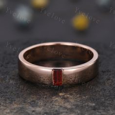 a gold ring with a red stone in the center on top of a granite surface