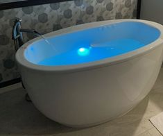 a white bath tub sitting on top of a tiled floor