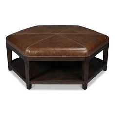 a brown leather ottoman sitting on top of a wooden table