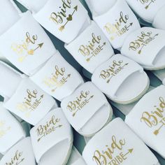 many pairs of white slippers with gold lettering on them