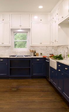 a kitchen with white cabinets and blue counter tops, wood flooring in the middle