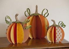 three paper pumpkins sitting on top of a wooden table