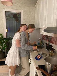 two girls are cooking in the kitchen together