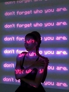 a woman standing in front of a wall with neon signs on it's side