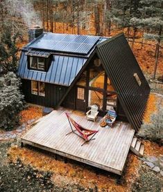 an aerial view of a small cabin in the woods with hammock and chairs