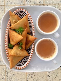 two cups of tea and some pastries on a plate