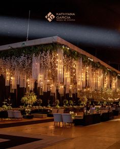 an outdoor event with lights and greenery on the walls, in front of a building at night