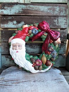 a christmas wreath sitting on top of a wooden chair with a santa clause face painted on it