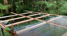 an image of a house being built in the woods with wood beams and glass walls