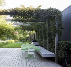 a wooden deck with green chairs under an arbor covered pergolated area next to it