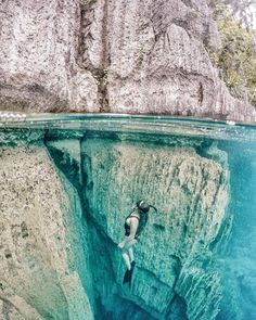 a person swimming in the water near some rocks